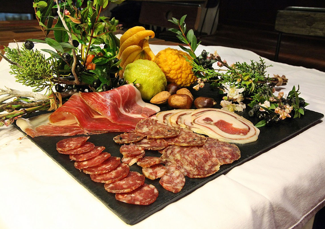 Extreme Nahaufnahme traditioneller korsischer Charcuterie und Käsespezialitäten auf einem rustikalen Holztisch